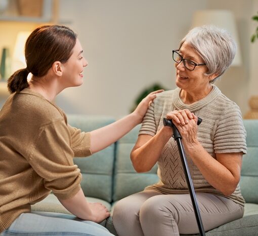 Elderly patient and caregiver spending time together. Senior woman holding cane.